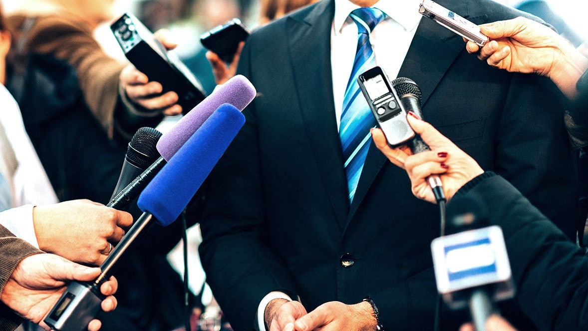 close up of businessman surrounded by microphones