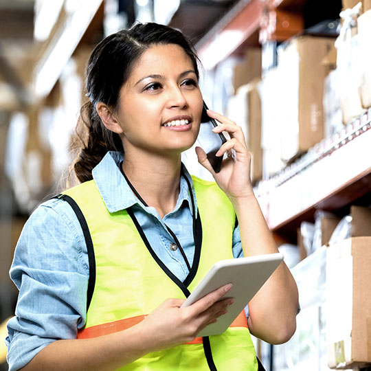 warehouse worker on the phone holding a tablet