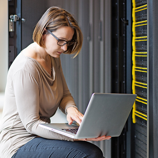 woman working on a laptop in a server room