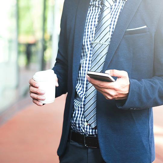Perché la stampa rimane essenziale businessman holding a coffee and mobile phone