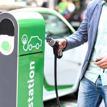 Il caricabatterie innovativo per veicoli elettrici man charging car at charging point